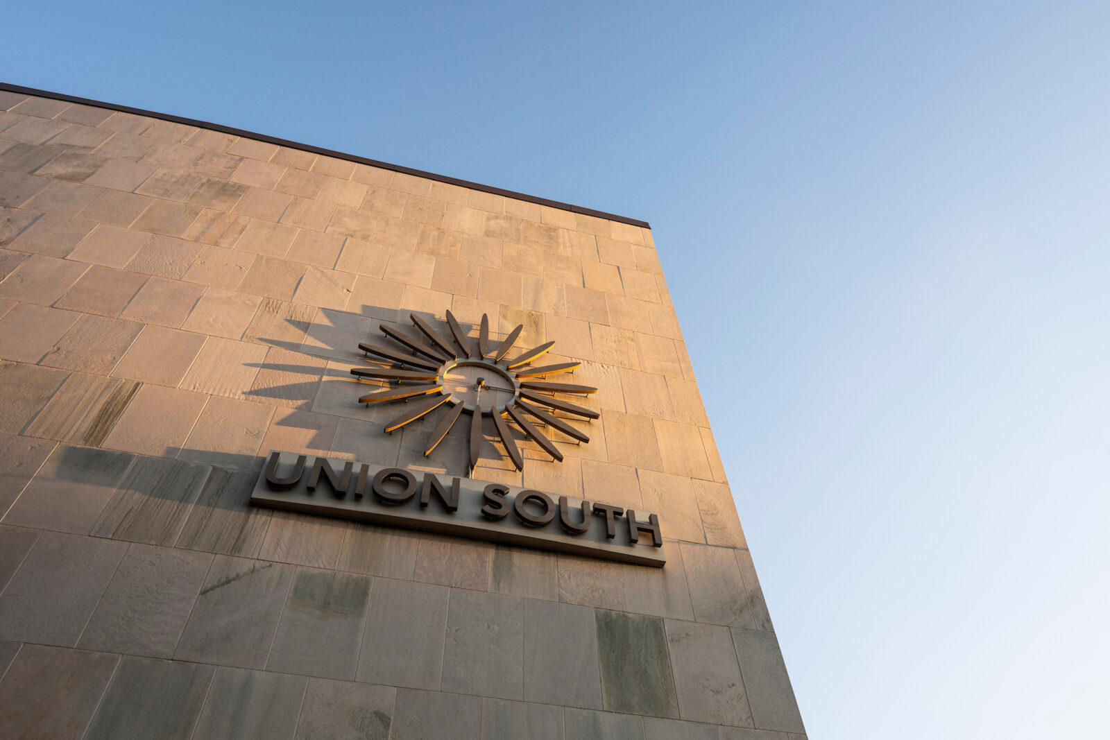 The sun sets on the building name and sunburst graphic outside of Union South.